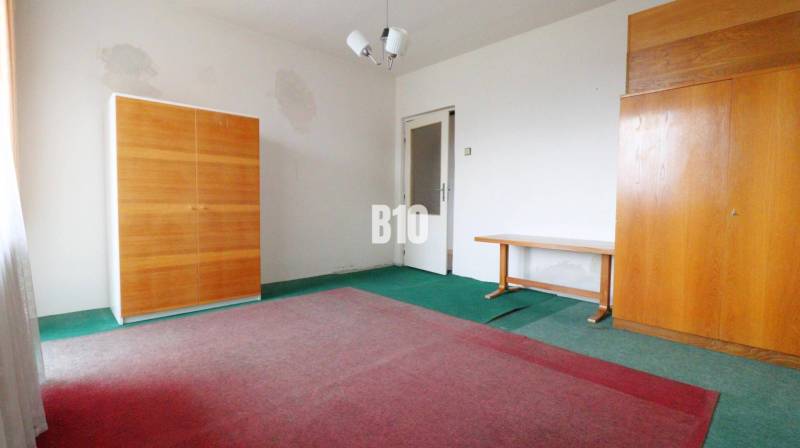 A room in a family house with carpets, two wardrobes, and a table.