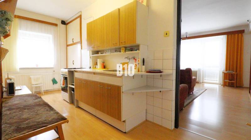 A kitchen in a family house with a wooden decor floor connected to the living room.
