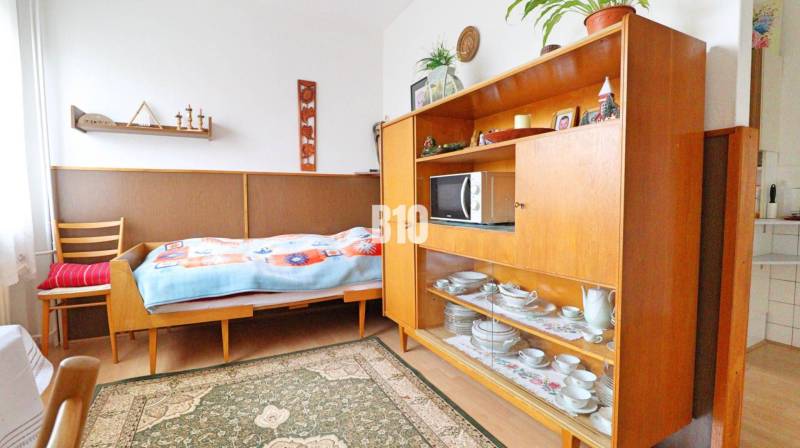 A room in a family house with a bed, a display cabinet, and a floor with a wooden decor.