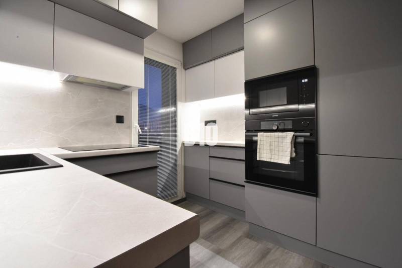 Kitchen in a 4-room apartment with built-in appliances and a wooden decor floor.