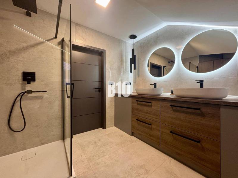 A bathroom in a 4-room apartment with two oval mirrors and a shower corner.