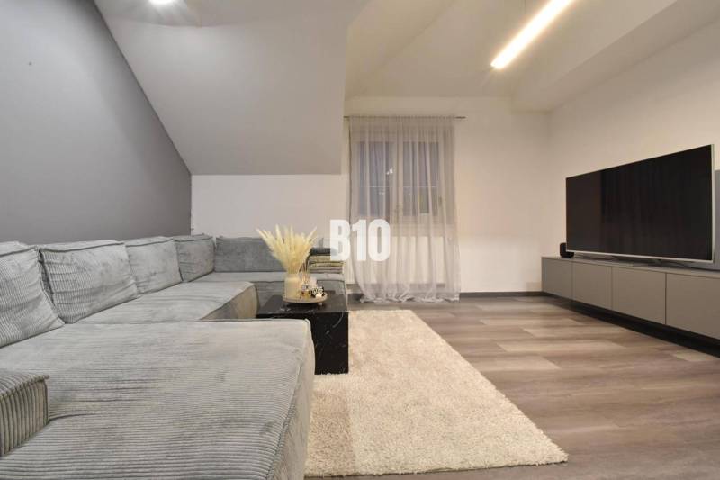 Living room with a corner sofa, television, and wooden decor flooring in a 4-room apartment.