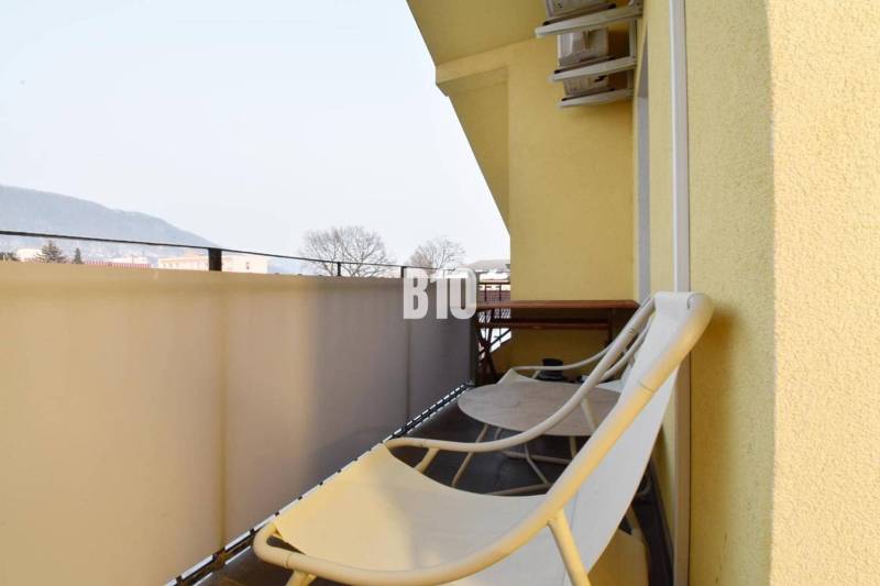 A balcony of a 4-room apartment in Žilina with chairs and a view of the mountains.