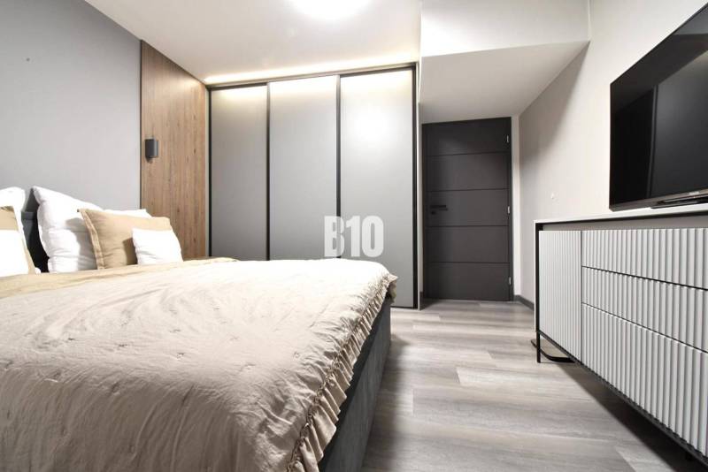 Bedroom with wood-patterned flooring and a wardrobe in a four-room apartment.
