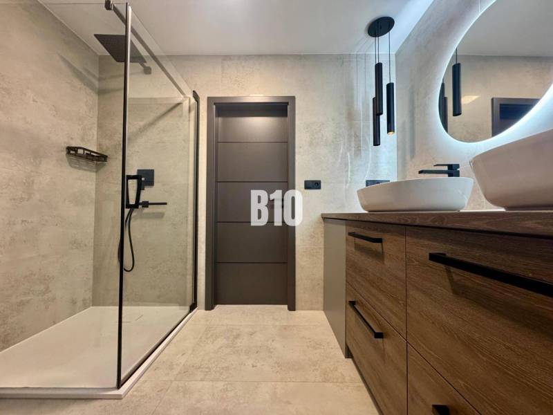 Bathroom in a 4-room apartment with an open shower and a floor with a wooden decor.