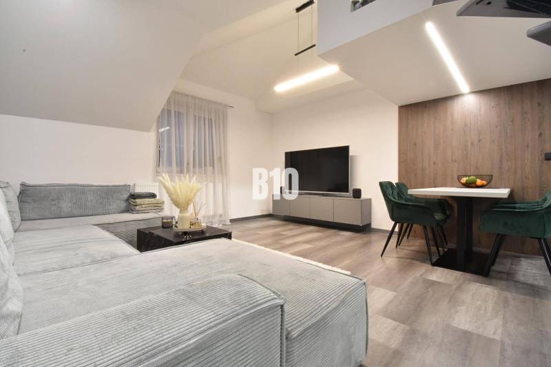 Living room in a 4-room apartment with a sofa, television, and wooden decor flooring.