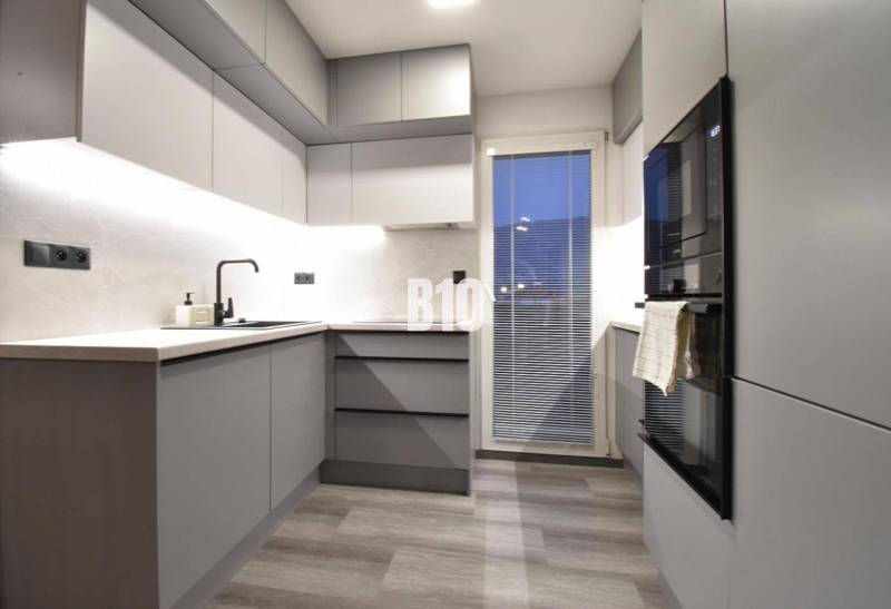 Stylish kitchen with grey furniture in a 4-room apartment, floor with wood decor.