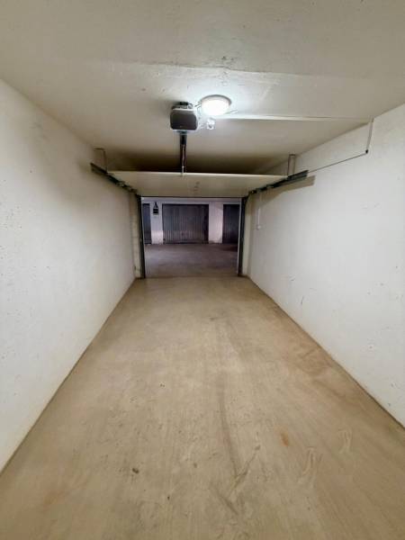 Closed garage space with a concrete floor and lighting.