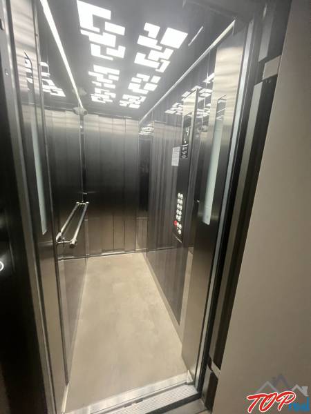 Elevator in a building with modern lighting and metal panels.