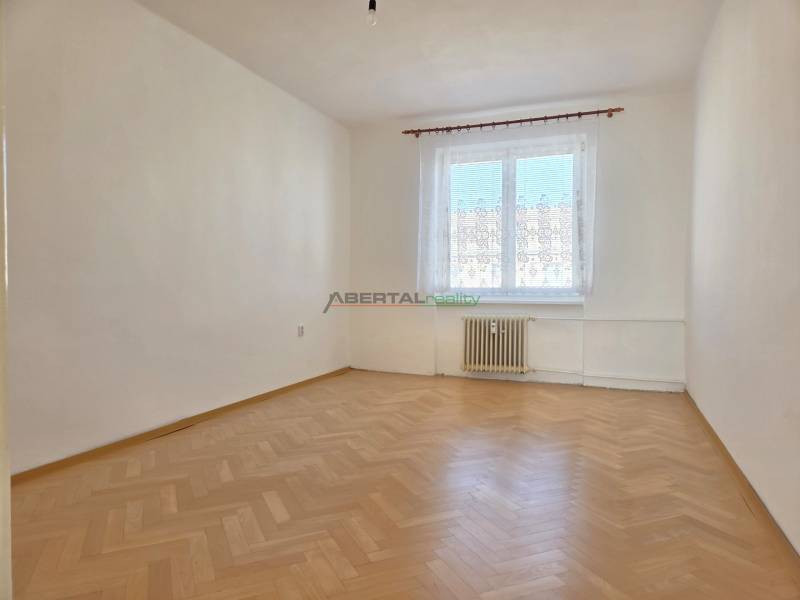 An empty room with a window and a wooden decor floor in a 3-room apartment.