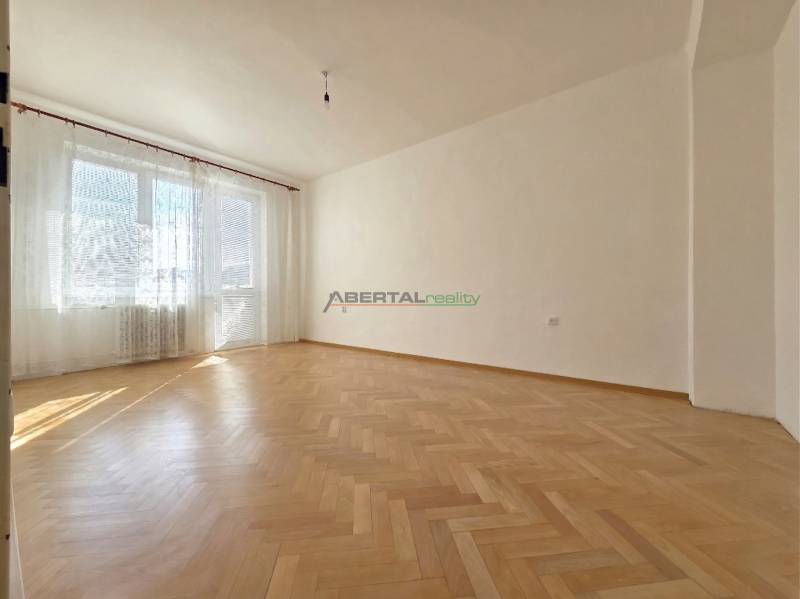 A spacious room with large windows and a wooden decor floor in a 3-room apartment.