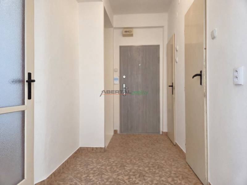 A hallway with tiles, white walls, and several doors in a 3-room apartment.