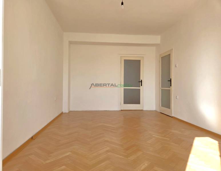 A room in a 3-room apartment has a wooden decor floor and white walls.