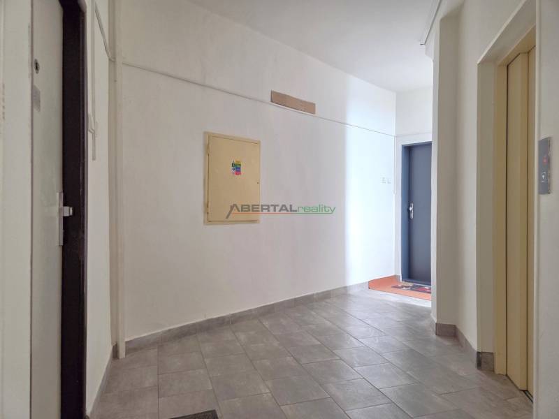 A hallway in a 3-room apartment with light-colored walls and gray tiles.