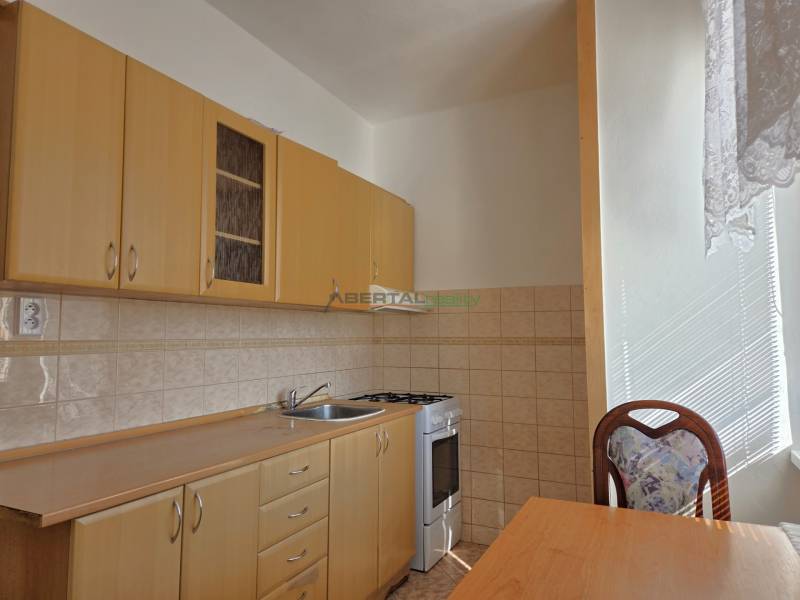 A kitchen with light furniture, a stove, and a table in a 3-room apartment.