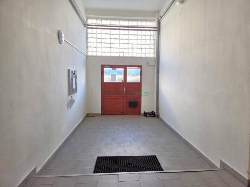 A hallway with tiles leading to red doors in a 3-room apartment.