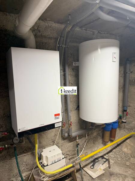Boiler with a water heater in the boiler room of a family house, including pipes and ducts.
