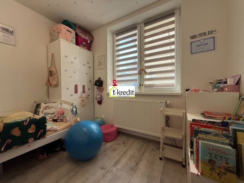 Children's room in a family house with a wooden decor floor, full of toys and books.