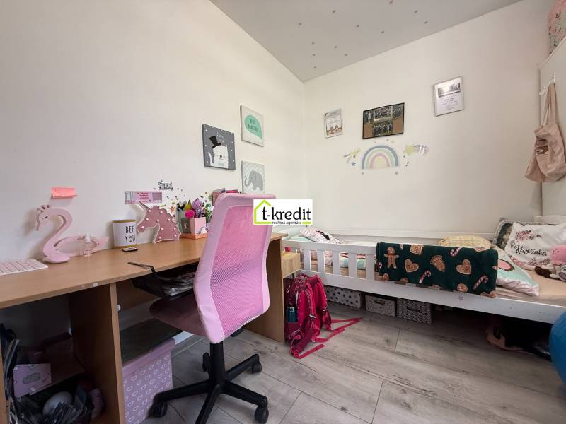 Children's room with a desk, pink chair, and a bed with decor for a child.