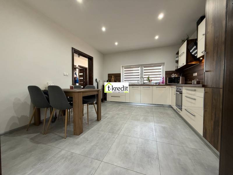 A kitchen in light colors with built-in appliances and a dining table in a family house.