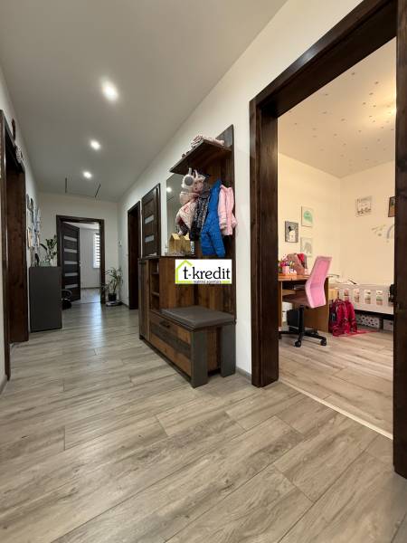 A hallway in a family house with a wooden decor floor, a work nook, and a coat rack wall.