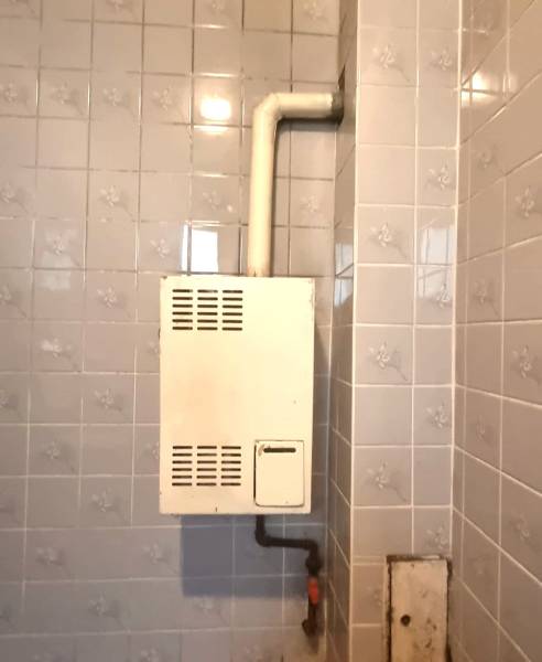 Bathroom in a family house with a gas boiler on tiles.