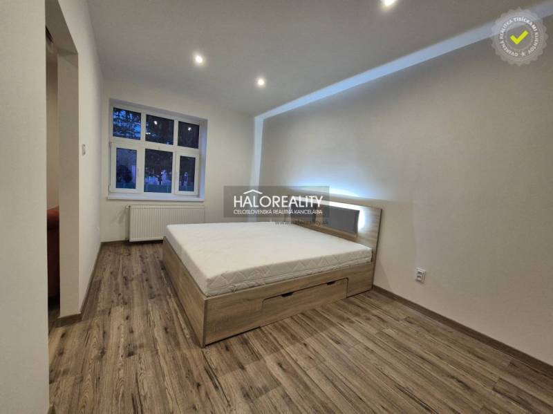Bedroom in a 2-room apartment with a bed and a wooden decor floor.