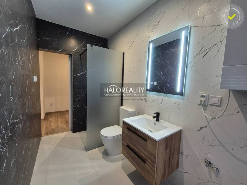 A bathroom in a 2-room apartment with black marble and a wooden decor floor.