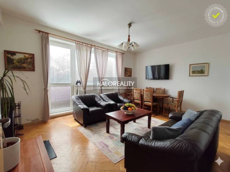 Living room with leather sofas and a television, with a wood-patterned floor.