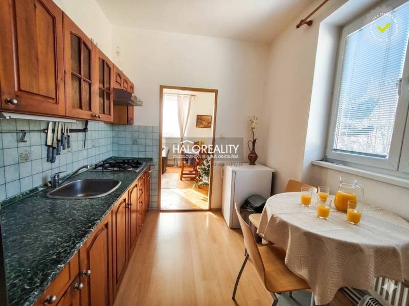 A kitchen in a 3-room apartment with wooden cabinets and a wooden decor floor.