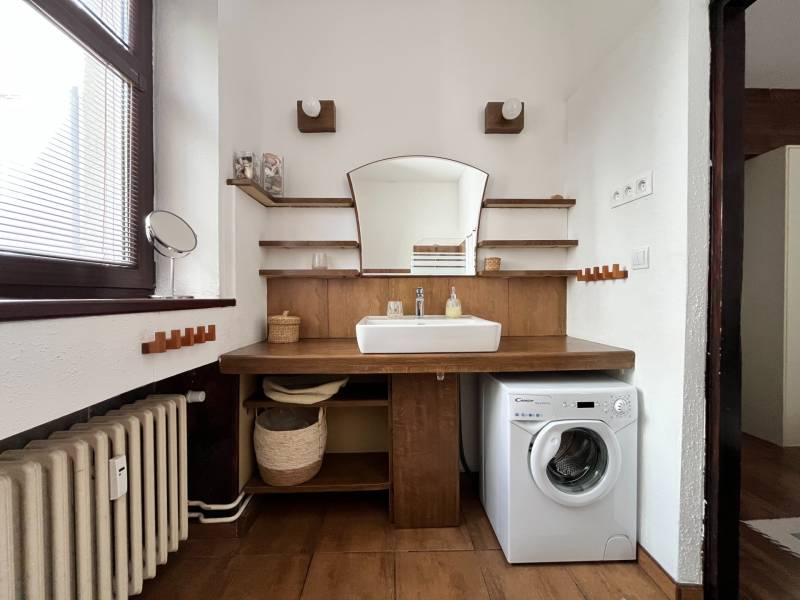 A bathroom in a 2-room apartment with wooden decor and a washing machine.