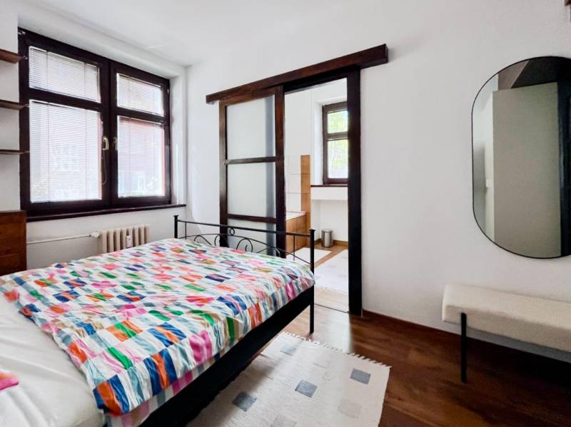 Bedroom in a two-room apartment with a bed and a mirror, floor with wooden decor.