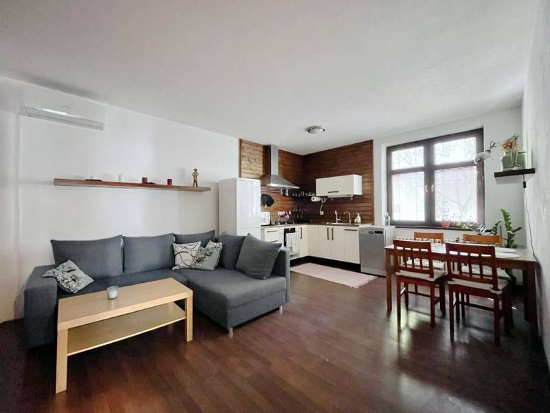 Living room with kitchen in a two-room apartment with a wooden decor floor.