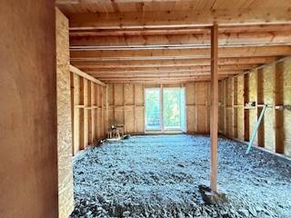 An unfinished interior of a cabin with a wooden structure and an opening for a terrace.