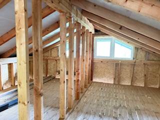 Attic with a window, wooden beams, and a floor with a wooden decor in a cottage.