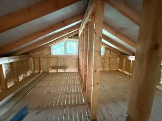 Attic space of the cottage with wooden beams and a floor with a wooden decor.
