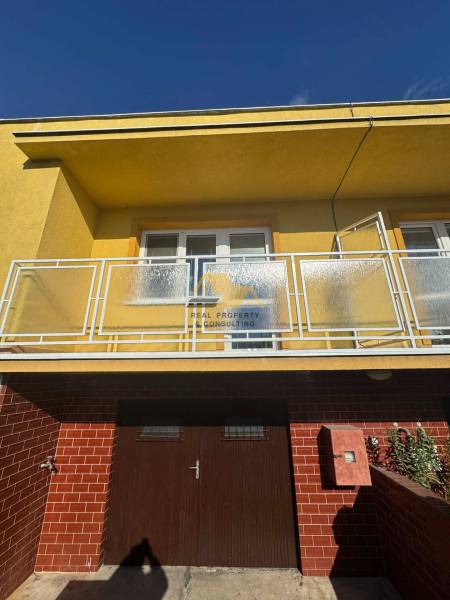 A family house in Nové Zámky on Nové Zámky Street with a balcony and brick cladding.