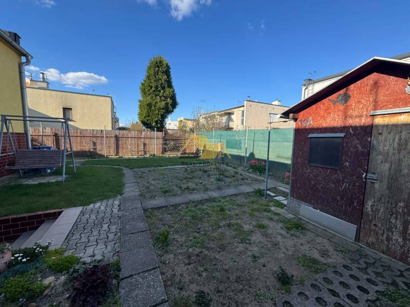 A garden with a lawn and a wooden house by a family home in Nové Zámky, Nové Zámky Street.