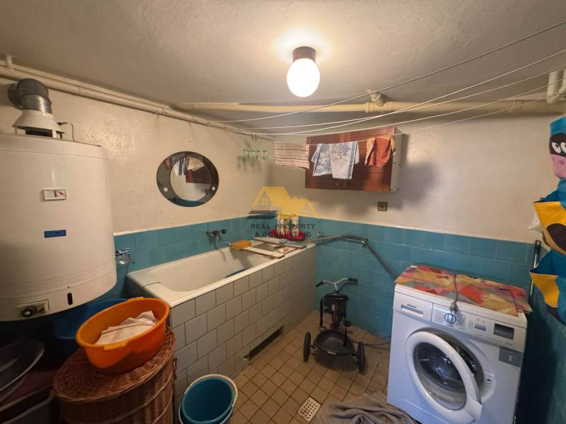 A bathroom in a family house with a bathtub, washing machine, and boiler, blue tiles.