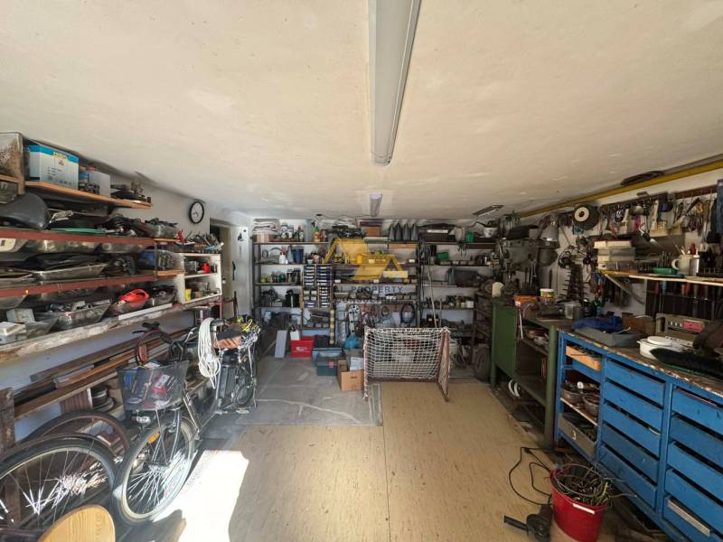 Workshop in a family house with tools, bicycles, and shelves full of materials.