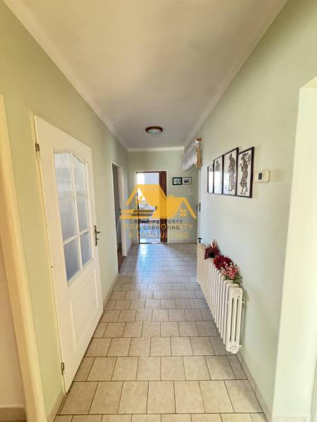A hallway in a family house with a tiled floor and simple wall decorations.