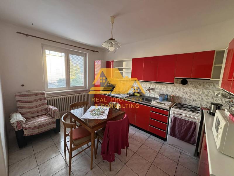 A kitchen with a red cabinet in a family house, equipped with a table and a chair.