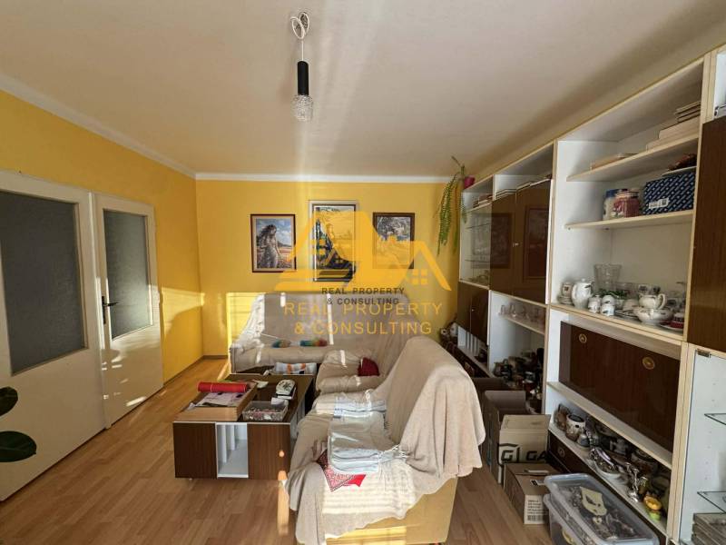 Living room in a family house with a white sofa, wooden decor flooring, yellow walls.