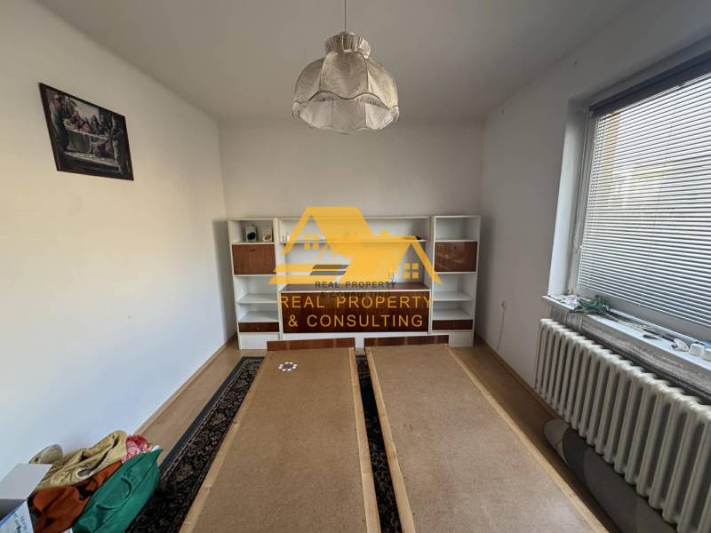 A room with a white wall, a shelving cabinet, and a wooden-patterned floor in a family house.