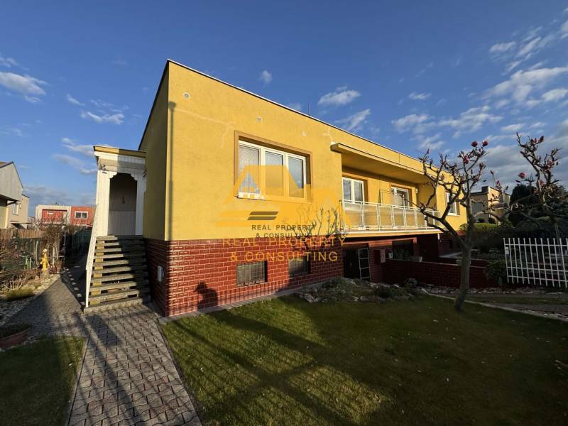 Yellow family house in Nové Zámky on a street with a landscaped garden and walkway.