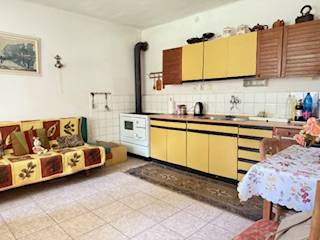A kitchen in a family house with beige kitchen cabinets and a tiled stove.