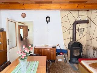 Interior of a family house with a tiled stove, wooden ceiling, and a dining table with flowers.