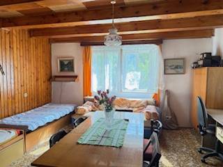 A room in a family house with wooden beams, a dining table, and two beds.