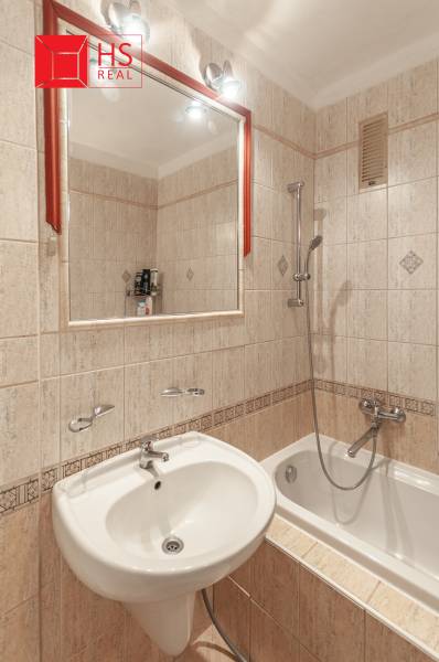A bathroom with a bathtub, a sink, and a mirror in a three-room apartment.