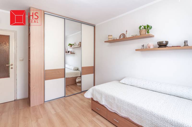 Bedroom in a 3-room apartment with a bed and a mirrored wardrobe, wooden decor flooring.